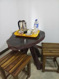 达瓦拉维Dew Safari Cottage的桌子和茶壶,旁边是两把椅子