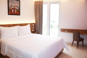 泗水Surabaya River View Hotel的酒店客房设有白色的床和窗户。