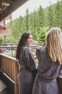 摩梭佩尔德罗霍夫阿尔卑斯生活方式酒店的两个女人站在阳台上互相看一看