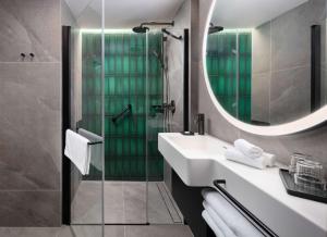 克拉科夫Hyatt Place Krakow的浴室配有盥洗盆和带镜子的淋浴