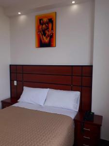 SangolquíHOTEL DEL RIVER MONUMENTO的一张带木制床头板的床,上面有一张图画