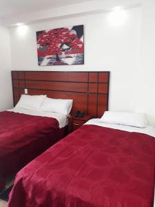 SangolquíHOTEL DEL RIVER MONUMENTO的两张位于酒店客房的床铺,配有红色床单