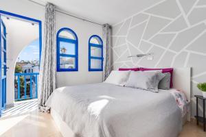 英格兰海滩Duplex Poolside Playa del Ingles的卧室配有白色的床和蓝色窗户。