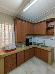 芙蓉Cozy Spacious seremban Bangalow Taman Rasah的厨房配有木制橱柜、水槽和微波炉