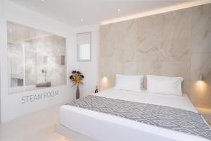 费拉Cycladic Suites的白色的卧室设有白色的床和墙壁