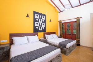 Eratnagoda库鲁甘加别墅旅馆的黄色墙壁客房的两张床