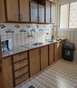 马斯喀特Farah Hotel Apartment的一个带木制橱柜和水槽的厨房