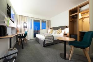 加来Holiday Inn Calais-Centre, an IHG Hotel的酒店客房带一张床、一张桌子和椅子