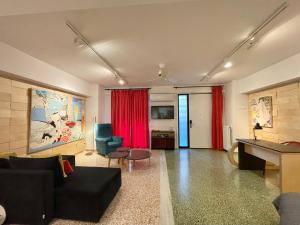 雅典Vouliagmeni Art Micro Loft的客厅配有黑色沙发和红色窗帘