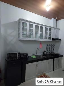 洛斯巴尼奥斯FLB Apartelle Los Banos的厨房配有白色橱柜和黑色台面