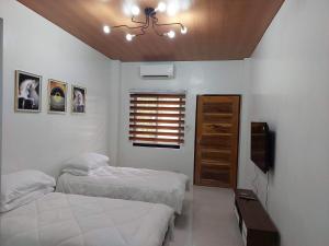 洛斯巴尼奥斯FLB Apartelle Los Banos的一间卧室设有两张床、一台电视和一扇窗户。