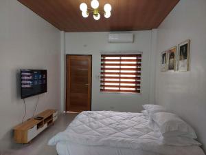 洛斯巴尼奥斯FLB Apartelle Los Banos的一间白色卧室,配有床和电视