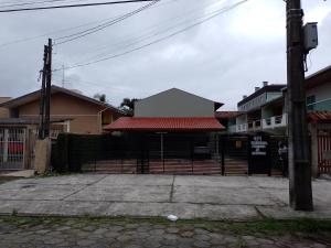 马蒂尼奥斯Casa Matinho Parana Praia Brava Praia Caioba Praia Mansa的建筑前的栅栏,有红色屋顶