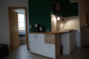 海特斯海姆Ferienwohnung Castellberg的厨房配有白色橱柜和绿色墙壁