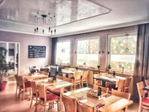 奥弗拉特祖尔艾赫酒店的餐厅设有木桌、椅子和窗户。