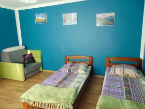 卡西纳维耶卡POD RÓŻĄ的蓝色墙壁的客房内配有两张床和一把椅子