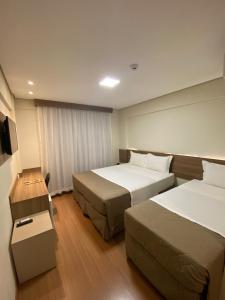 Nova AndradinaHotel B&S的酒店客房设有两张床和一张桌子。