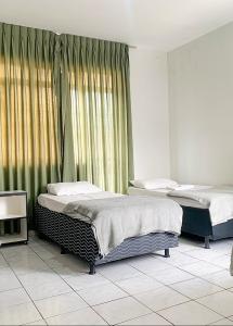 阿纳波利斯Hotel Central de Anápolis的两张床铺,位于带窗帘的房间