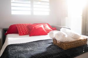 Rémire-CampT1 Les Fleurs de Coco的一间卧室配有一张带红色枕头和毛巾的床。