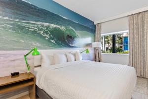 圣徒皮特海滩海滩明信片旅馆的一间卧室配有一张床,并拥有一幅大幅的海洋画