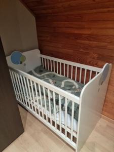 哈勒maison de vacances的木墙房间内的白色婴儿床
