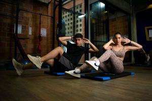 麦德林Los Patios Hostel的两个女人和一个男人坐在健身房的运动垫上