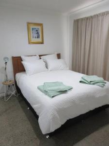 本迪戈The Artist's Cottage的卧室配有白色床和绿色毛巾