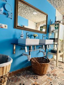 马拉加Cortijo el Alcornocal的浴室设有水槽和蓝色墙壁上的镜子