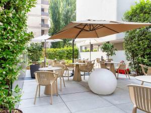 洛迦诺宜必思洛迦诺酒店的一个带桌椅和遮阳伞的庭院