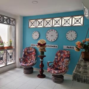 卡塔赫纳Luna Cartagena Airport Hotel的一间墙上有两把椅子和钟的房间