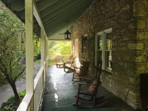 SharpsburgLock Keepers Cottage on C&O Canal/Potomac River的石屋上带摇椅的门廊