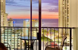 檀香山珍妮小屋威基奇公寓的阳台享有海景,配有桌椅。
