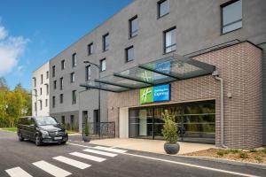 贝利罗曼维利而Holiday Inn Express - Marne-la-Vallée Val d'Europe, an IHG Hotel的停在大楼前的汽车