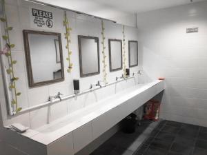哥打京那巴鲁Capsule Inn的浴室设有一排盥洗盆和镜子