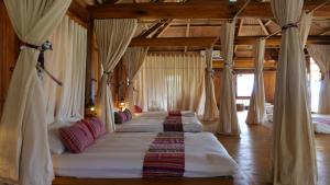 枚州县Nha Tan - Mai Chau Homestay and Tours的一间卧室设有四张带窗帘的床