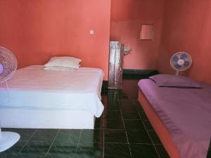 龙目岛库塔Perwita Homestay的红色墙壁客房的两张床