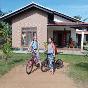 帕西库达Aiden Homestay的两个人站在房子前面,骑着自行车