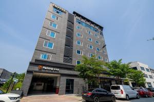原州市Wonju Central Hotel的停车场内有车辆停放的高楼