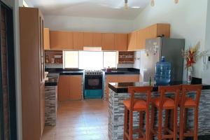 皮乌拉La casa de Alex的厨房配有木制橱柜和带酒吧凳的台面。