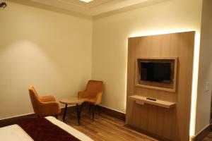 阿姆利则Hotel Crown Savoy, Near Railway Station & GURU NANAK DEV UNIVERSITY的酒店客房带电视和两把椅子