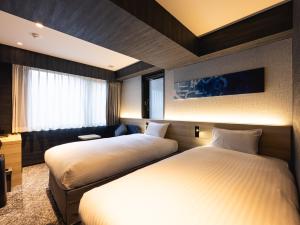 京都La'gent Hotel Kyoto Nijo的一间卧室设有两张床和窗户。