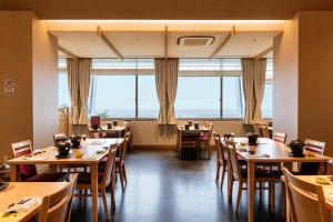 MihamaKAMENOI HOTEL Chitamihama的餐厅设有桌椅和大窗户。