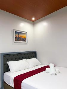 桑托斯将军城ICON Venue and Suites的卧室配有一张带白色床单的床,墙上挂着一幅画