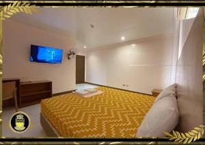杜马格特White Knights Real的卧室配有一张床,墙上配有电视。