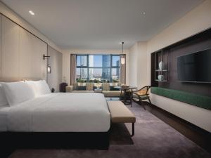昆山HUALUXE Kunshan Huaqiao, an IHG Hotel - F1 Racing Preferred Hotel的配有一张床和一台平面电视的酒店客房