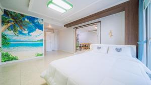 巨济Geojerowa Pension的卧室配有白色的床和海洋绘画