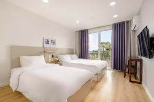 西归浦市Cordelia Hotel的酒店客房设有两张床和窗户。
