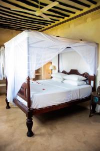 拉穆LAMU HOUSE的卧室配有带白色床单和枕头的天蓬床。