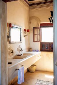 拉穆LAMU HOUSE的一间带两个盥洗盆和两个窗户的浴室