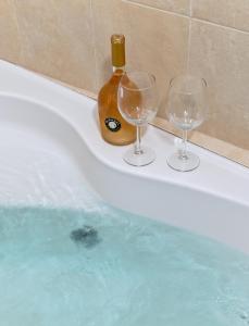 提比里亚Atlantis luxury apartment first line to sea of galelli的浴缸里备有两杯葡萄酒和一瓶葡萄酒